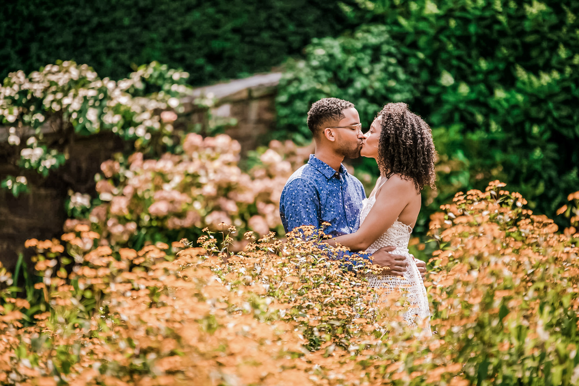 Couple kissing while being surrounded by foliage