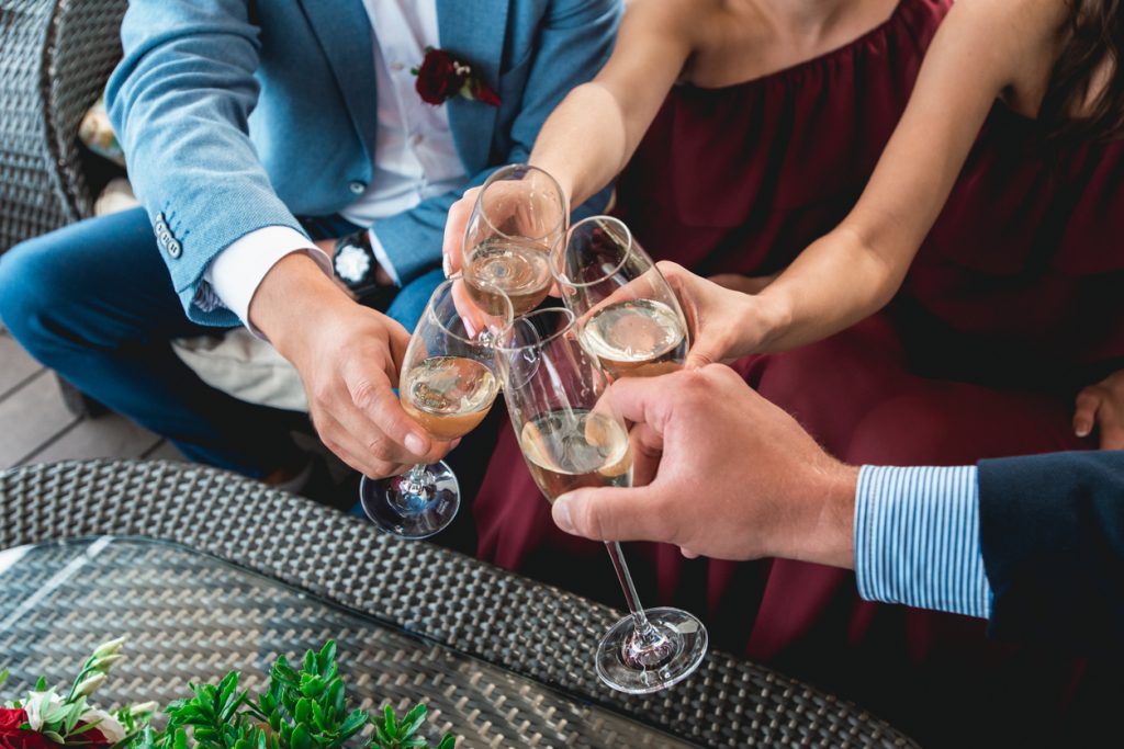 couple and bridal party holding white wine glasses